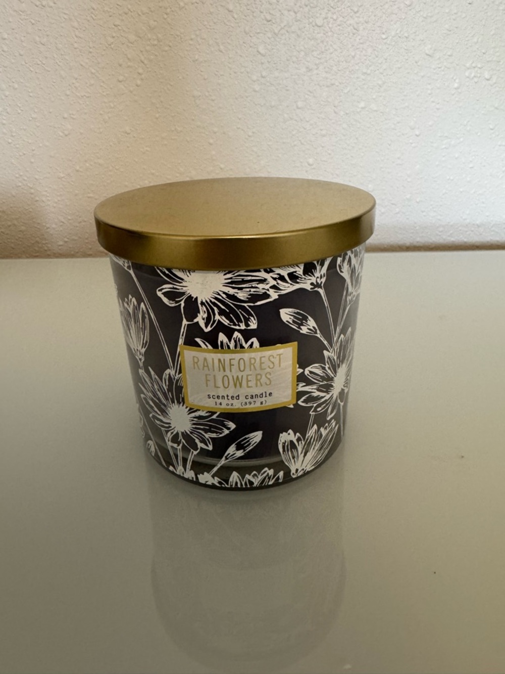 RAINFOREST Black and White Floral Candle with Gold Lid, never used, 14 oz